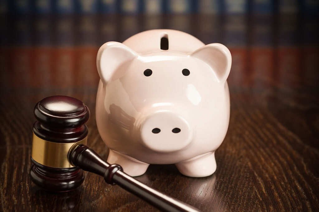 Piggy bank with a judge’s gavel on a wooden table, symbolising estate and succession planning for wealth preservation.