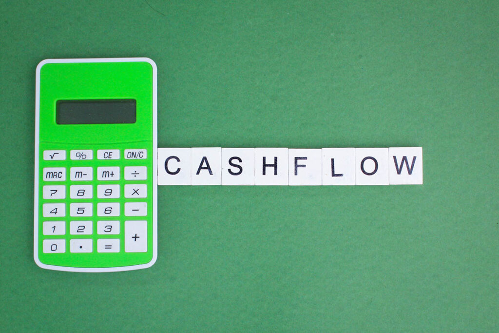 Green calculator with the word CASHFLOW spelled in letter tiles, symbolising liquidity management and financial planning.