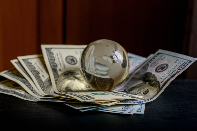 Glass globe resting on US dollar banknotes, symbolising private capital deployment and global investment strategies.