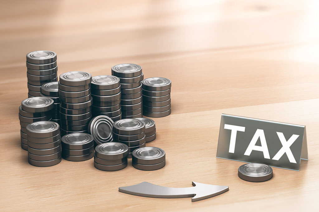 Stacks of coins with an arrow pointing towards a tax sign, symbolising tax regulatory structuring and financial compliance strategies.